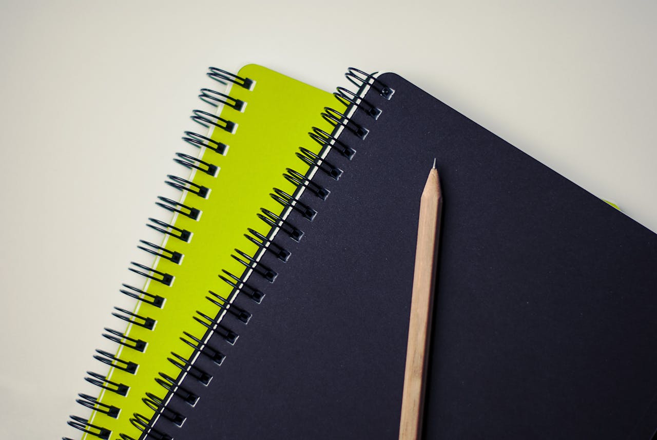 Close-up of spiral-bound notebooks with a pencil, perfect for creative projects.