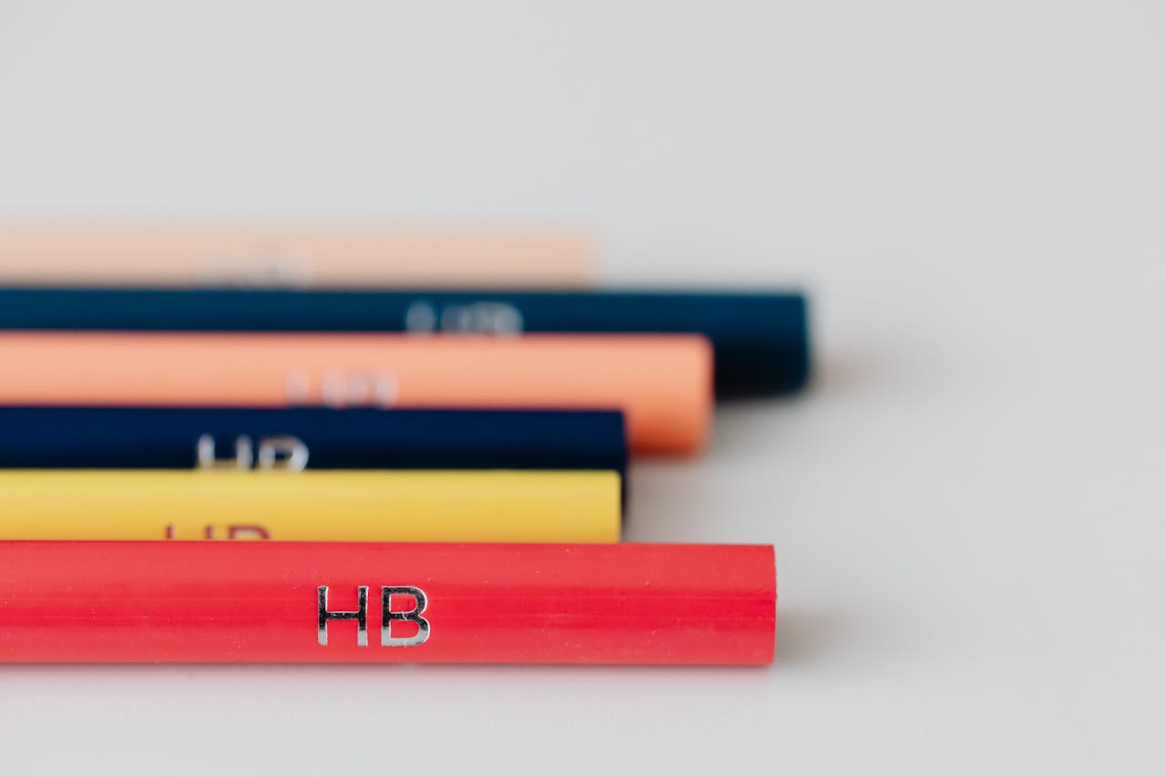 Close-up of vibrant HB pencils arranged on a white surface with selective focus.